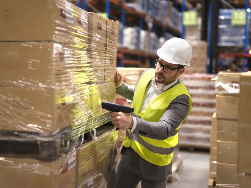 male warehouse worker using bar code scanner to analyze newly arrived goods for further placement in storage department scaled