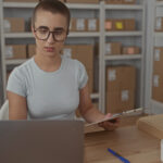 Profissional conferindo packing list e mercadorias em processo de expedição logística