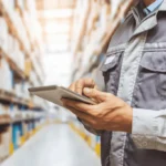 Profissional utilizando sistemas de estoque em tablet para controle de armazém