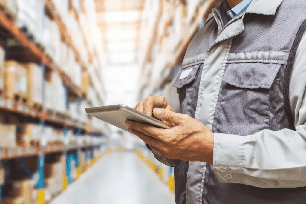 Profissional utilizando sistemas de estoque em tablet para controle de armazém